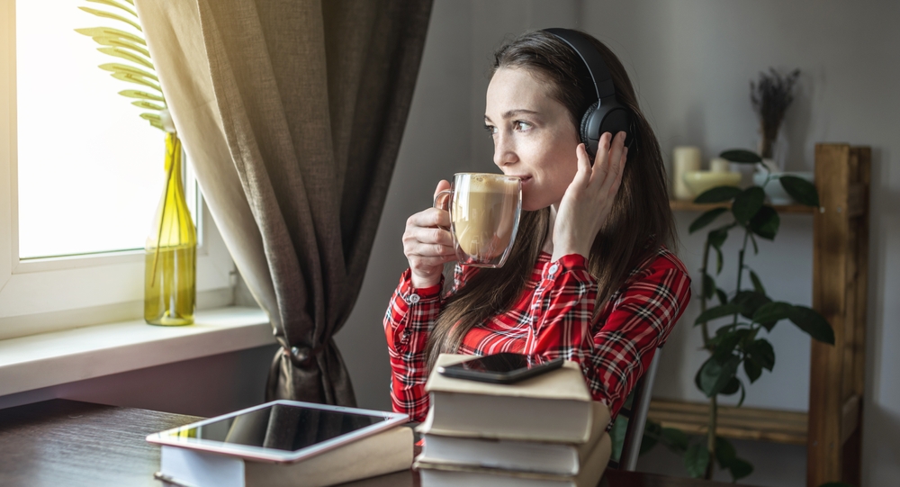 mujer bebiendo cafe mientras escuchar audiolibro
